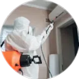 a man in ppe kit spraying chemical in a house for infection from covid and other viruses