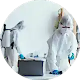 two men in ppe kit spraying disinfection chemical inside a room