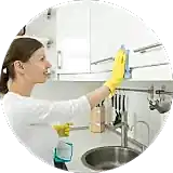 girl spraying cleaner and wiping a kitchen cup board