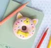 Doughnut-shaped dog eraser placed on a notebook beside coloured pencils