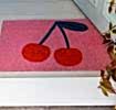 doormat featuring red cherry print in a pink background