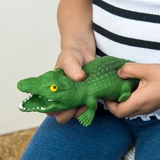 Child squeezing a green crocodile toy