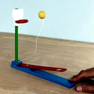 wooden tabletop basketball game with a lever launching a yellow ball toward a hoop