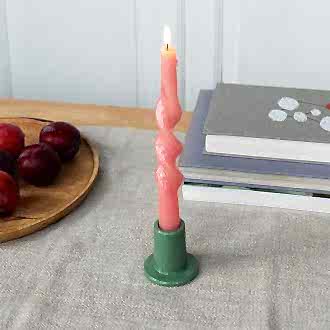 Khaki ceramic candle holder with a cylindrical shape and wide flat base, holding a lit pink candle