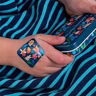 Plaster applied to a kids' hand with a fairies in the garden-themed design.