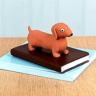 Squeezy squishy toy shaped like a brown sausage dog with floppy ears and a cute face placed on the book.