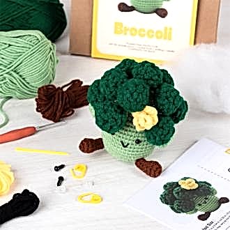 Crochet kit packaging placed beside finished crocheted broccoli