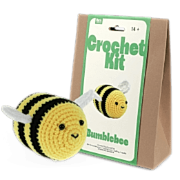 Crochet kit packaging and finished crocheted bee beside it