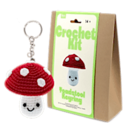 Crochet kit packaging displayed next to a finished red and white toadstool mushroom keychain