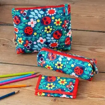 Floral and Ladybird-patterned pencil cases and matching stationery items displayed on a wooden surface—ideal for school or home use.