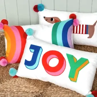 Embroidered cushion with pom poms