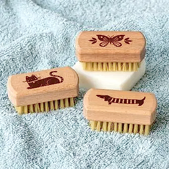 three Wooden nail brush with engraved designs of a butterfly, a cat, and a sausage dog