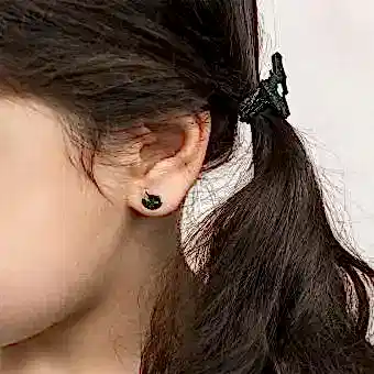 girl wearing small black cat-shaped earring