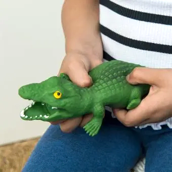 Child squeezing a green crocodile toy