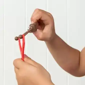 Red slingshot with a sticky, poop-shaped held by a child