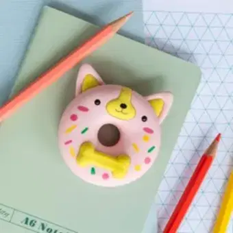 Doughnut-shaped dog eraser placed on a notebook beside coloured pencils