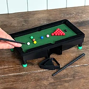 Table top snooker game set up with balls, cues, and rack