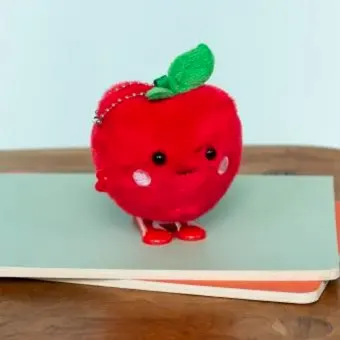 Red apple-shaped plush wind-up toy with a smiling face and a green leave on top