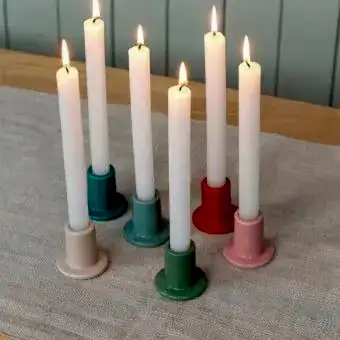 mixed ceramic candle holder with a cylindrical shape and a wide, flat base, holding a lit candle