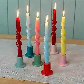 mixed ceramic candle holder with a cylindrical shape and a wide, flat base, holding a lit candle