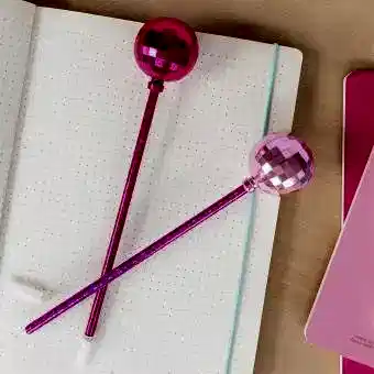 two dsico ball pens in pink placed on a notebook