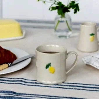 Stoneware mug featuring a yellow lemon print with green leaves and handle 