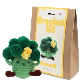 Crochet kit packaging placed beside finished crocheted broccoli