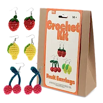 Crochet kit packaging placed beside three finished crocheted earrings shaped like strawberries, lemons, and cherries