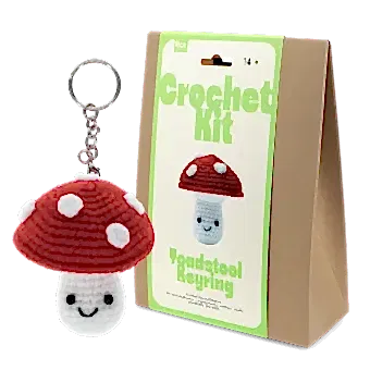 Crochet kit packaging displayed next to a finished red and white toadstool mushroom keychain