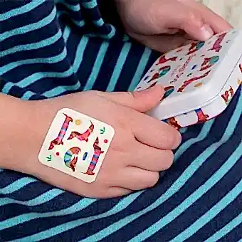 Plaster applied to a kids' hand with a sausage dog-themed design.