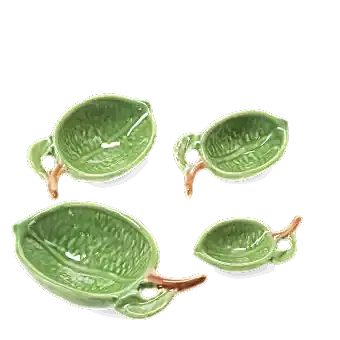 Set of four ceramic measuring spoons shaped like green leaves with brown stem handles 