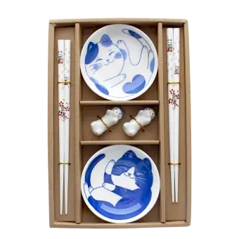 Two cat-themed dipping bowls, two pairs of chopsticks, and two cat-shaped rests in a brown box